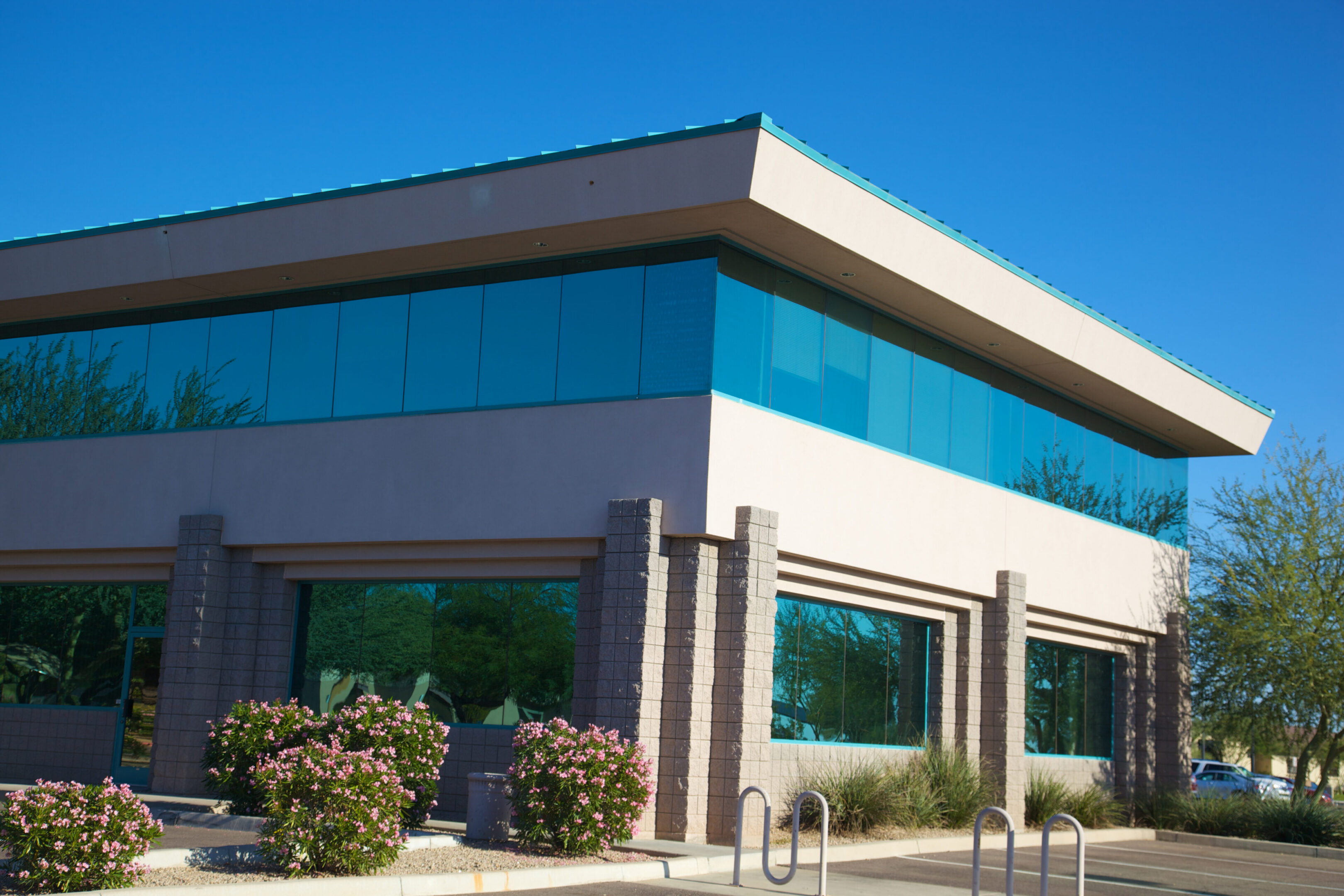 Modern blue glass Scottsdale Arizona business building on a clear day with acacia trees set on a bright blue clear sky background